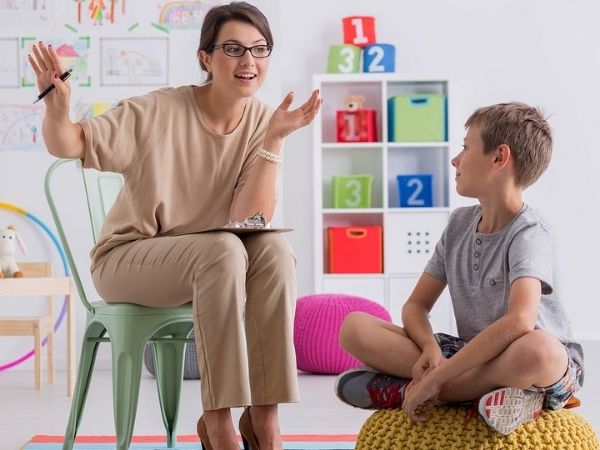 Woman talking to a smiling boy with toys and shelves in the background, promoting special educational needs support.